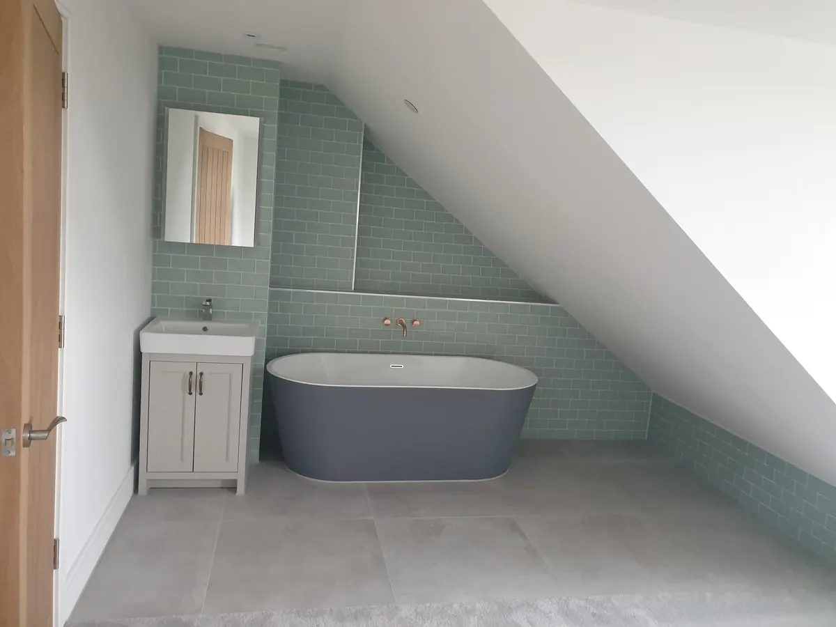 Loft bathroom renovation with freestanding bath and green tiling